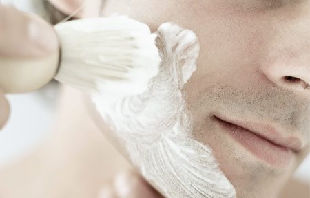 Homme appliquant de la crème à raser sur son visage