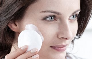 Femme appliquant le lait nettoyant sur un coton