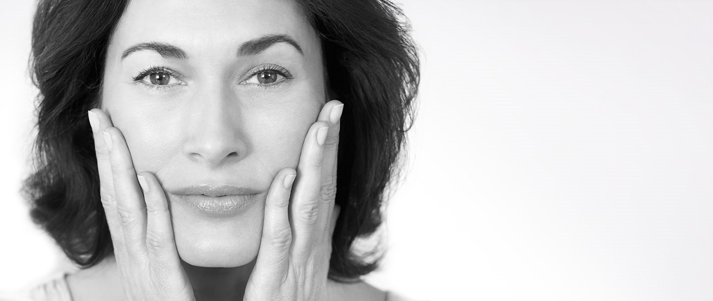 Femme d'âge mûr se touchant les joues avec les deux mains.