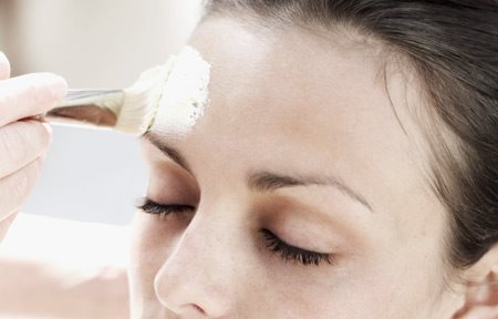 Application d'un peeling au pinceau sur un visage de femme
